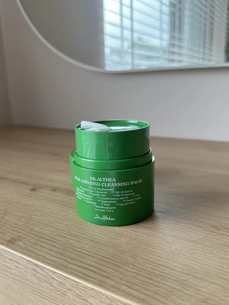 Opakowanie Dr. Althea Pure Grinding Cleansing Balm z widoczną listą składników i wysuniętym kawałkiem balsamu.